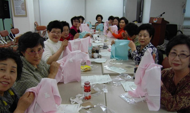 배냇저고리 사랑나눔캠페인 기념촬영 모습. 자신이 만든 배냇저고리를 들고있는 자생인들의 모습